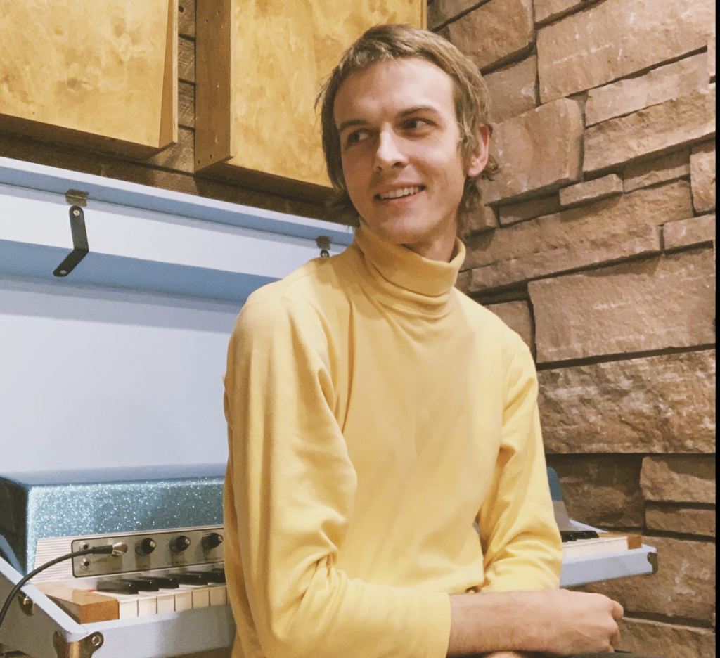 jay maike in front of a 1970s fender rhodes keyboard in a turtleneck